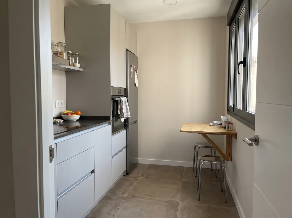 Cocina de unos 8 m² en línea con una mesa abatible junto a la pared (imagen generada con IA).
